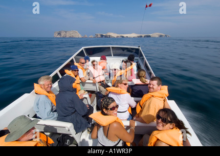 Tourists on their way to visit the Ballestas Islands (top of the image) in the Paracas National Reserve, Peru, on a speed boat. Stock Photo