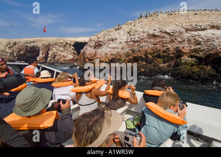 A view from a guided boat trip to the Ballestas Islands as tourists take photographs of the wildlife. Stock Photo