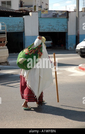 Old woman carrying bag on the street in Gabes city in Tunisia Stock Photo