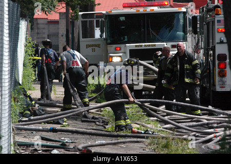 Firefighters fighting a fire House fire firefighter job with many hoses on ground and truck Stock Photo