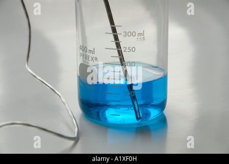 A computer interfaced digital sensor measuring the temperature of a blue chemical in a beaker Stock Photo