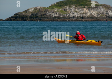 Yellow canoe with man in red jacket sailing near shore with Scottish island in the background, UK, Europe Stock Photo