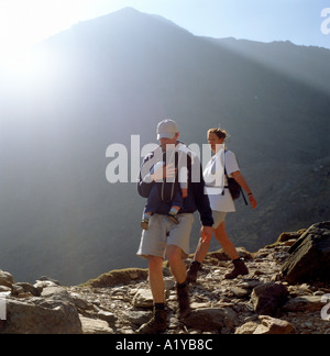 A young dad carrying his baby in a carrier hiking with mum on Pyg track  Mount Snowdon in Snowdonia National Park  North Wales UK   KATHY DEWITT Stock Photo