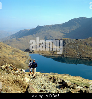 Young couple walking with a baby descending a rough trail Snowdon Gwynedd North Wales UK    KATHY DEWITT Stock Photo