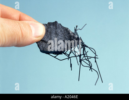 A piece of lodestone, or magnetite, picking up bits of iron wire with magnetic force in a school physics experiment. Stock Photo