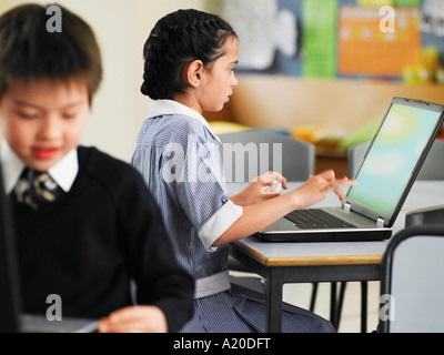 Elementary students using laptops in classroom Stock Photo