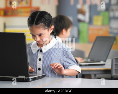 Elementary schoolgirl using laptop in classroom Stock Photo