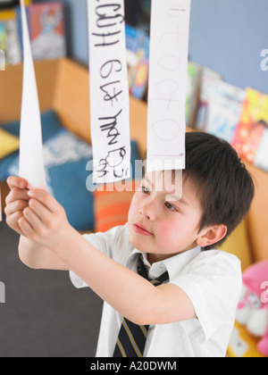 Elementary schoolboy learning to read from hanging paper strip in classroom, elevated view Stock Photo
