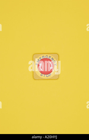 Emergency stop button on yellow wall Stock Photo