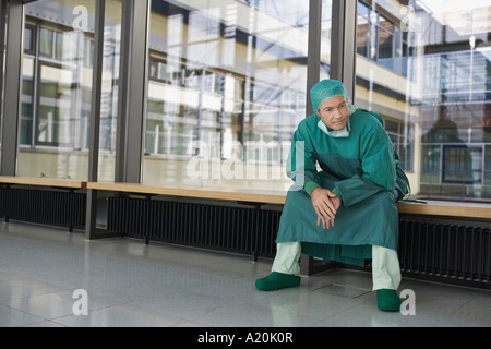 Pensive Physician sitting in hospital corridor Stock Photo