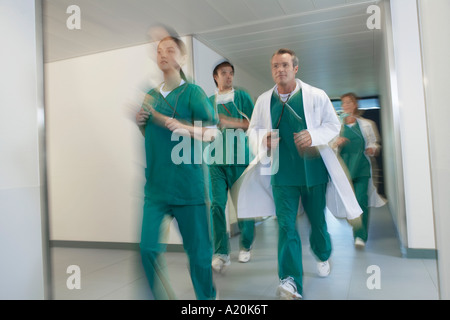 Motion blur image of small group of doctors and nurses in scrubs running through hospital corridor Stock Photo