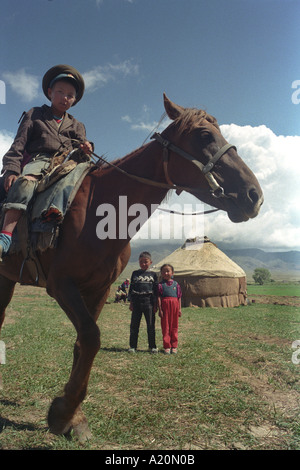 Young boy on a horse in front of their familys yurt, near Lake Issyk Kul, Kyrgyzstan Stock Photo