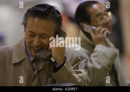 Japanese businessmen known as salarymen using pay phones and mobile telephones, Tokyo, Japan Stock Photo