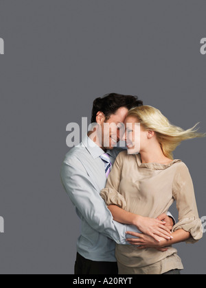 Smiling Young Couple embracing, hair blowing in breeze Stock Photo