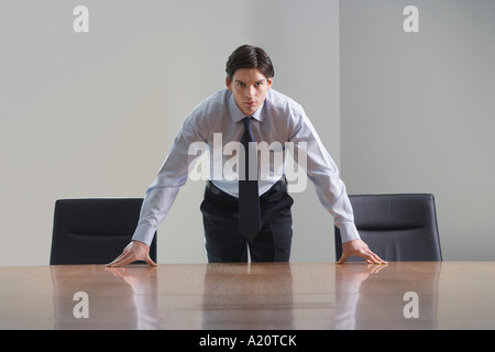 Businessman standing and leaning over conference room table Stock Photo