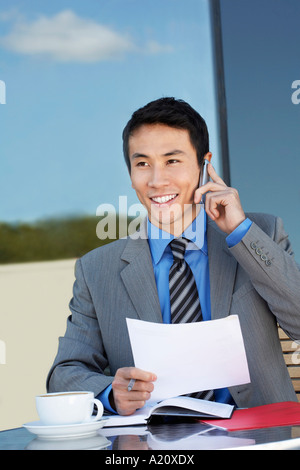 Businessman at outdoor Cafe, talking on phone, reviewing documents Stock Photo