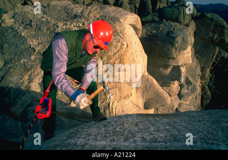 A worker removes sealer from an old crack in the top of George Washington head prior to filling the crack with new material Stock Photo
