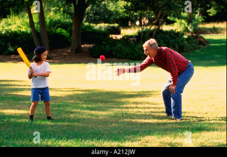 Grandfather pitching a ball to his grandaughter Stock Photo