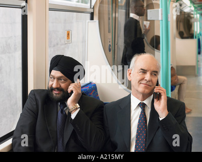 Businessmen sitting on commuter train, Using Cell Phones Stock Photo