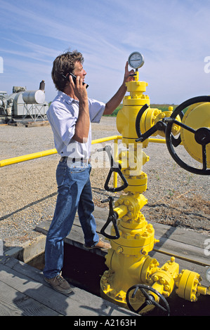 released technician in field phones gauge readings back to office using cell phone Stock Photo