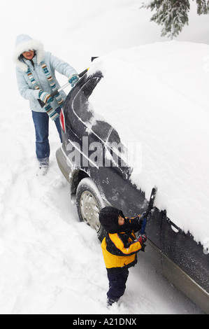 Mother and Son Brushing Snow off Van Stock Photo