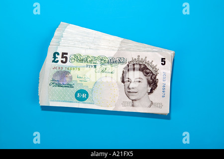 Pile of British five 5 pound bank notes on blue Stock Photo