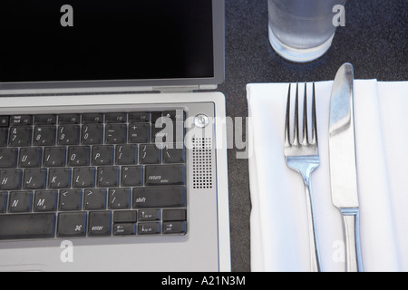 Laptop Next to Place Setting Stock Photo