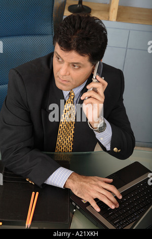 Executive Boss sitting in his cabin talking on mobile phoneand smiling Stock Photo