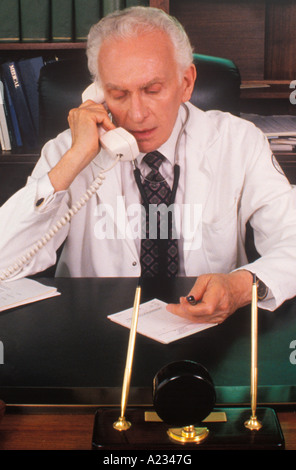 Doctor in His Office At His Desk Talking On the Telephone To Patient Stock Photo