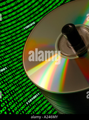 Close up of a stack of CD DVD disks on a Dutch angle with a curved field of binary code Stock Photo