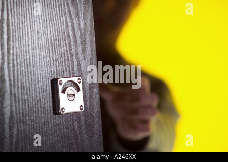 Privacy lock on public toilet door yellow background Stock Photo