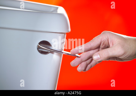 Toilet Flush Lever with hand against red background Stock Photo
