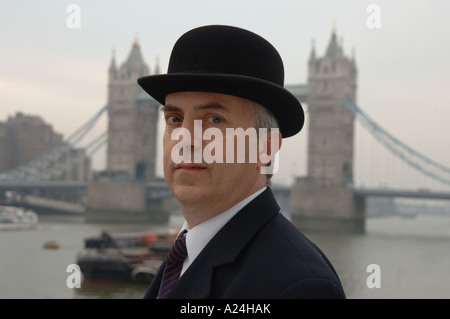 Traditional English city gent in suit and bowler hat by Tower Bridge, City of London, UK. Stock Photo