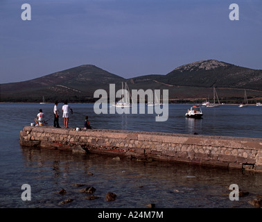 Fishermen on stone jetty at Porto Conte Sardinia Stock Photo