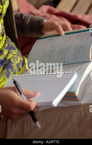 Close up of Woman studying and taking notes while sitting on park bench Stock Photo