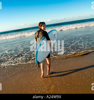 A surfer walks with his board to the sea at Playa Bruja Mazatlan Sinaloa Mexico Stock Photo