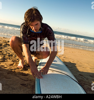 A surfer waxes his board on the Playa Bruja beach in Mazatlan Mexico Stock Photo