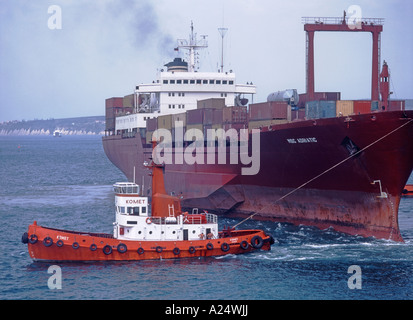 Koper, Primorska, Slovenia. Tug boat pulling large container ship in Koper Harbour Stock Photo