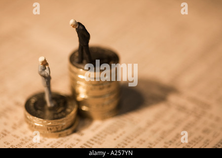 Miniature businessmen standing on coins on financial newspaper Stock Photo