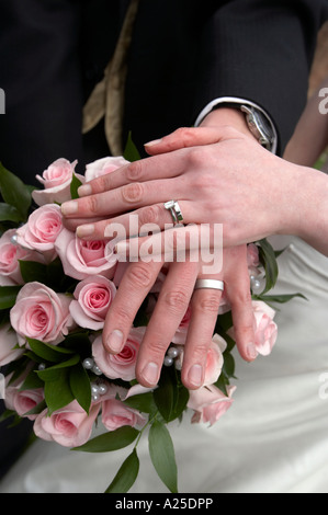 The hands of a couple who have just got married (showing rings and bridal bouquet) Stock Photo