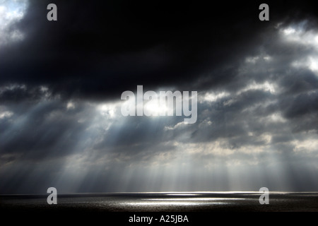Shafts beams of sunlight coming through clouds out to sea Stock Photo