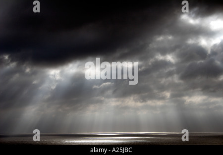 Shafts beams of sunlight coming through clouds out to sea Stock Photo