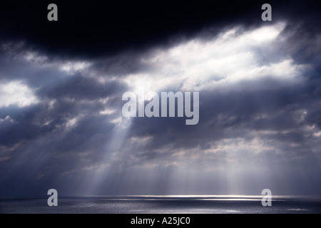 Shafts beams of sunlight coming through clouds out to sea Stock Photo