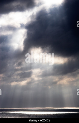Shafts beams of sunlight coming through clouds out to sea Stock Photo