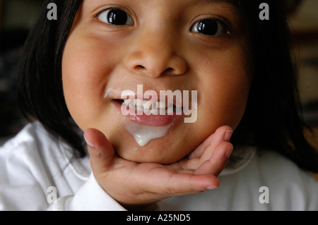 A three year old Mayan baby girl making happy facial expression while wearing a milk moustache milk mustache Stock Photo