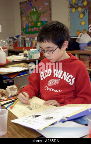 Smiling 3rd grade elementary student working on a project at their desk Stock Photo