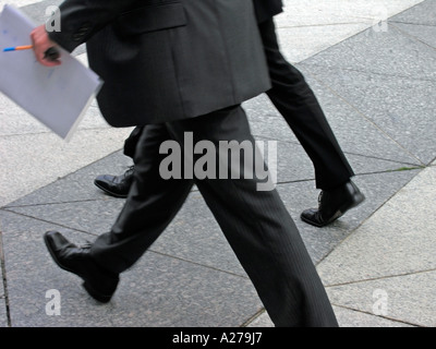 two men businessmen in black suits and notice book in hands going unerringly on street Stock Photo