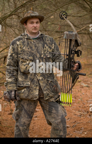 A deer hunter dressed in camo clothing hunting from a tree stand in a ...