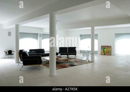 Living area with black seating and interior columns in minimalist warehouse conversion Stock Photo