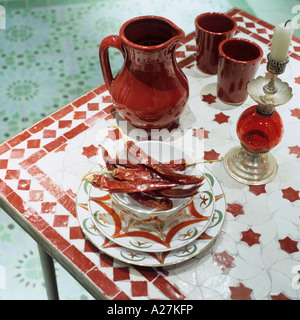 Red jug and chillies on tile topped table in the medina in marrakesh Stock Photo